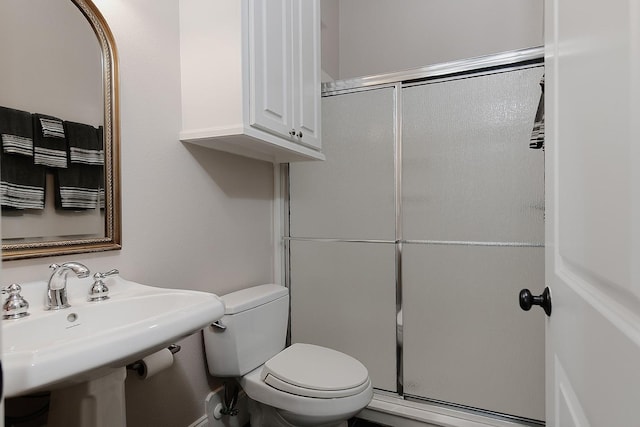 bathroom with a sink, a shower with shower door, and toilet