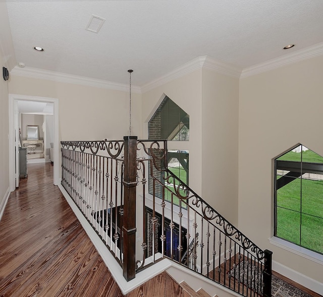 corridor featuring visible vents, crown molding, baseboards, an upstairs landing, and wood finished floors