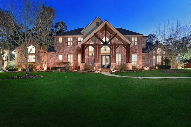 tudor home with brick siding and a front lawn