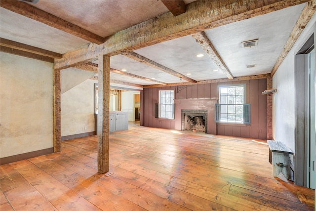 unfurnished living room featuring wood-type flooring, a fireplace, and beam ceiling