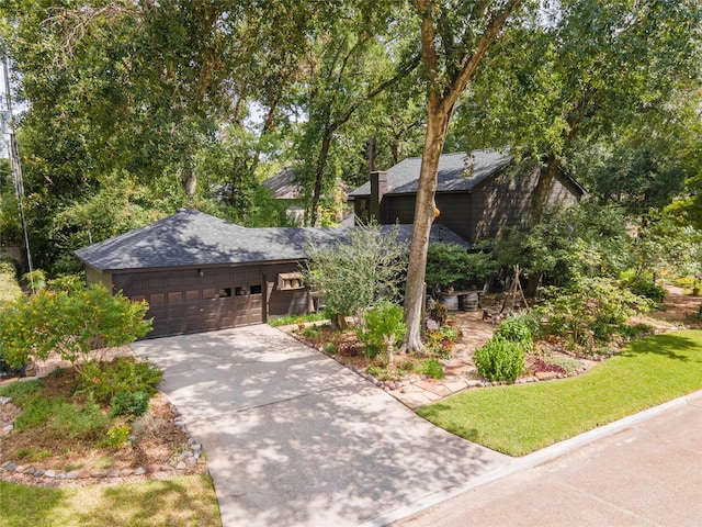 view of front facade with concrete driveway, roof with shingles, and an attached garage