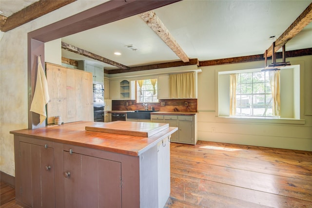 kitchen with a peninsula, wood counters, a sink, beam ceiling, and light wood finished floors