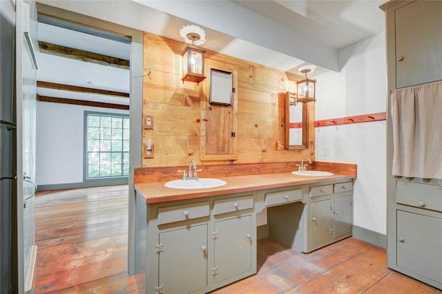 full bath featuring beam ceiling, a sink, and wood-type flooring