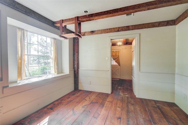 spare room with beam ceiling, visible vents, and wood-type flooring