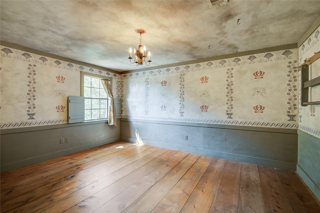 spare room featuring baseboards, an inviting chandelier, and wood-type flooring