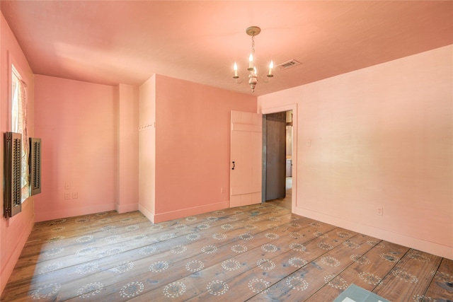 empty room with visible vents, hardwood / wood-style flooring, and a notable chandelier