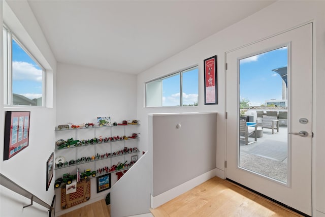 doorway with baseboards, plenty of natural light, and light wood finished floors