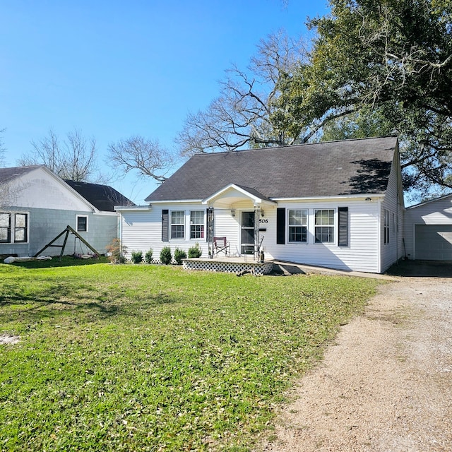 view of front facade featuring dirt driveway, an outbuilding, and a front yard