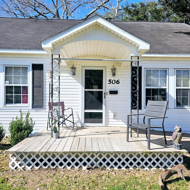 property entrance with a shingled roof and a deck