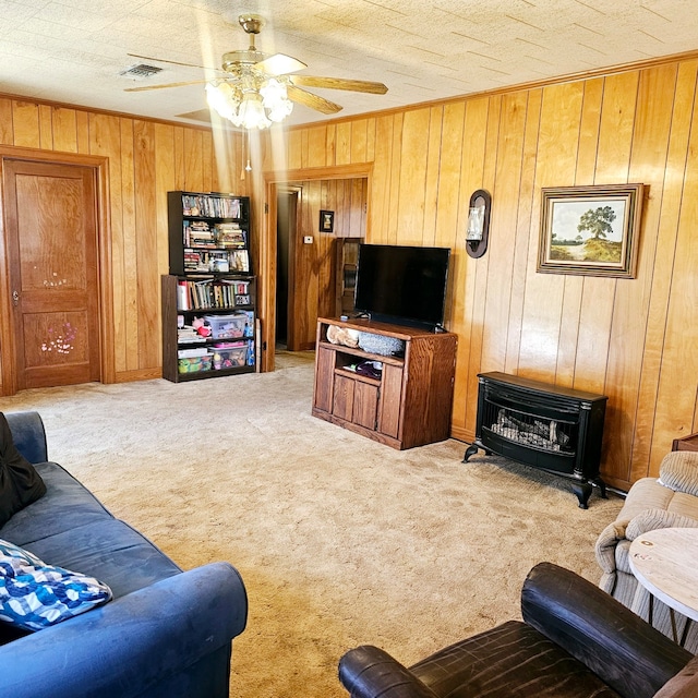 living area with wooden walls, visible vents, a ceiling fan, carpet, and a textured ceiling