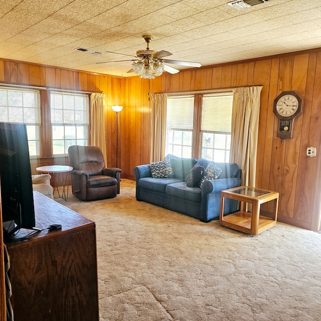 living room featuring wood walls, a ceiling fan, and carpet flooring