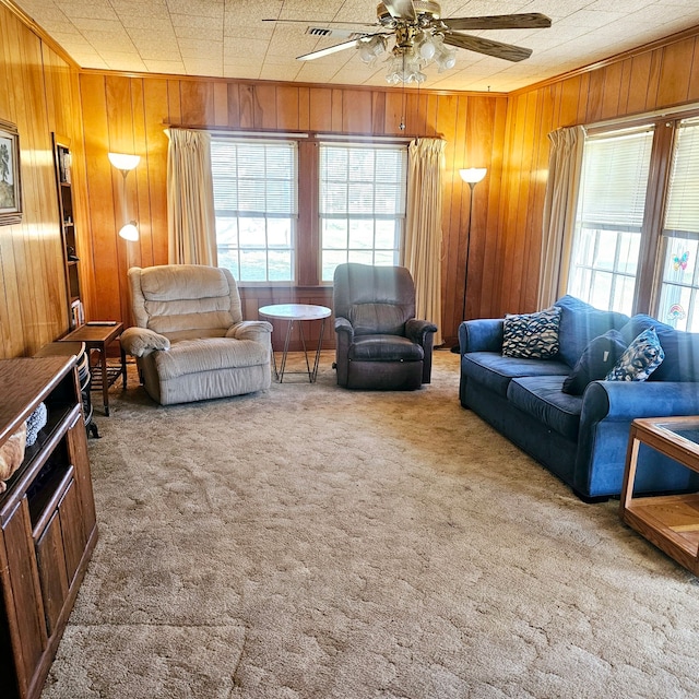 carpeted living area featuring wood walls and a ceiling fan