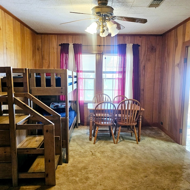 carpeted bedroom featuring ornamental molding, visible vents, and wooden walls