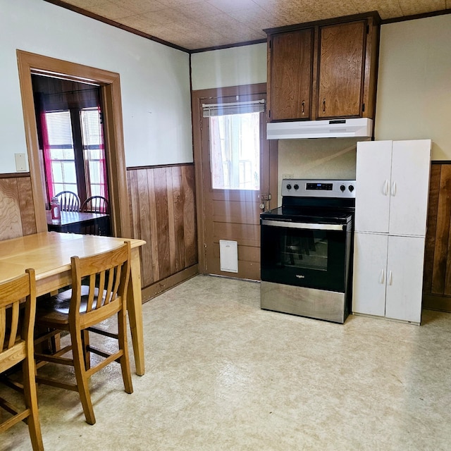 kitchen featuring wooden walls, a wainscoted wall, under cabinet range hood, electric range, and light floors