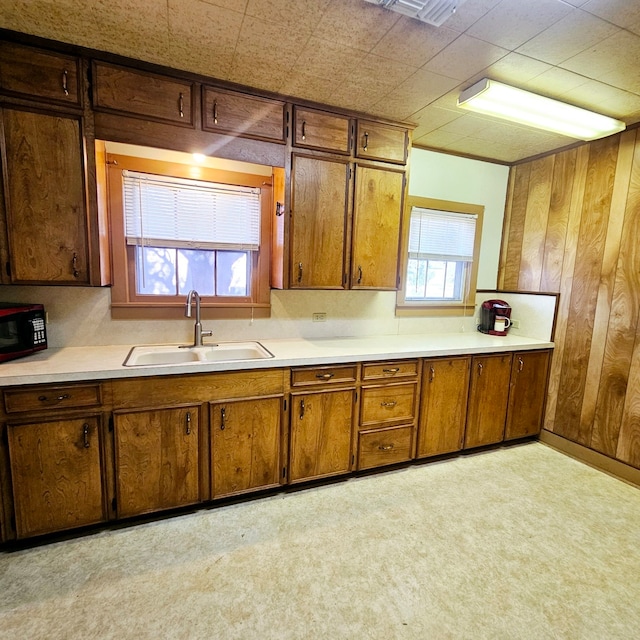 kitchen featuring brown cabinetry, black microwave, light countertops, and a sink