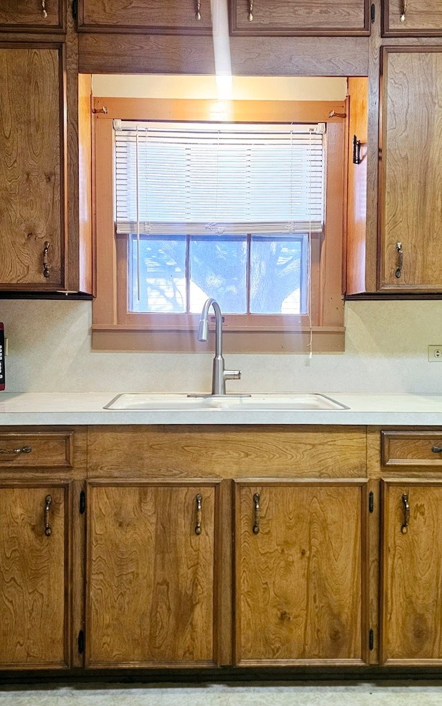 kitchen featuring brown cabinetry, a sink, and light countertops