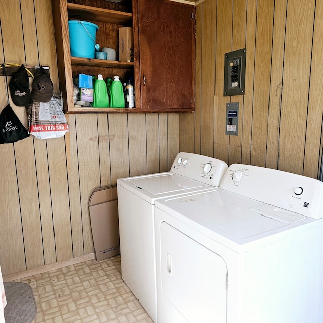 laundry area featuring cabinet space, wooden walls, and separate washer and dryer