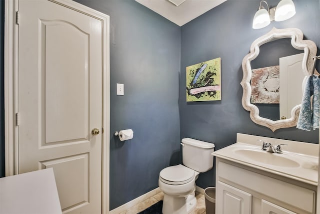 half bathroom with tile patterned flooring, baseboards, vanity, and toilet