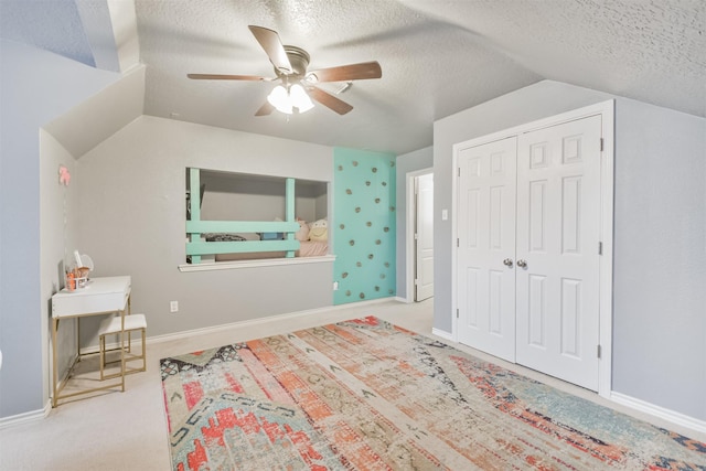 carpeted bedroom featuring a textured ceiling, a closet, lofted ceiling, and baseboards