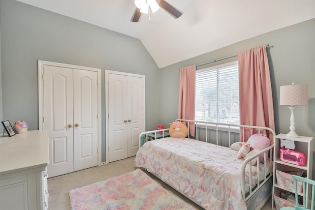 carpeted bedroom featuring a ceiling fan, vaulted ceiling, and two closets