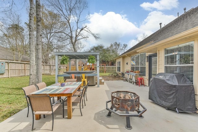 view of patio with an outdoor fire pit, outdoor dining area, a fenced backyard, a grill, and a hot tub