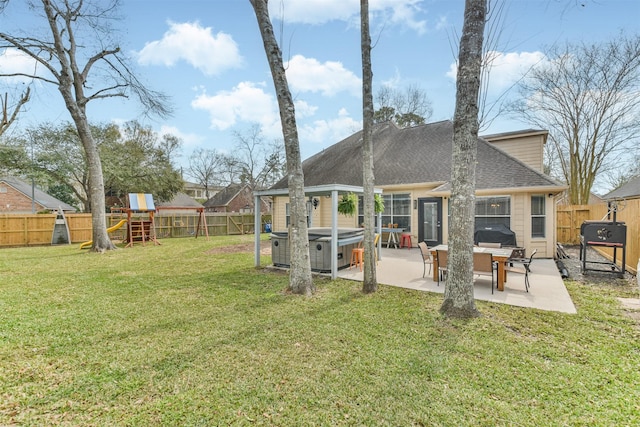 back of property featuring a hot tub, a playground, a fenced backyard, and a patio