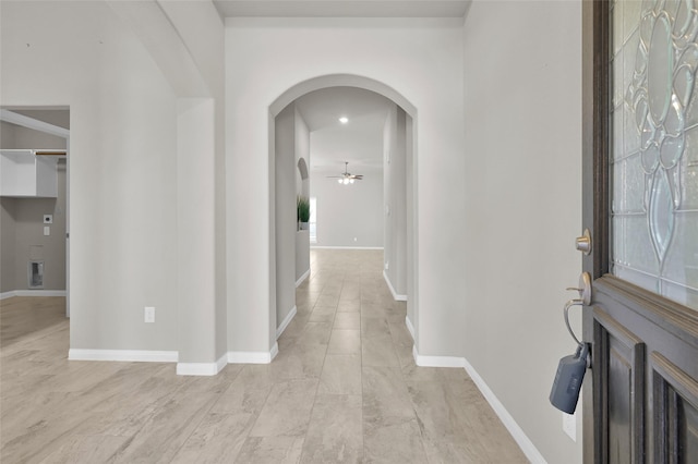 entryway with arched walkways, a ceiling fan, and baseboards