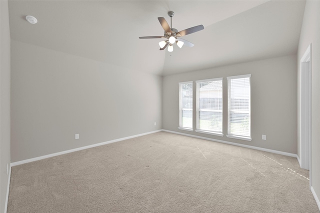 spare room featuring light carpet, baseboards, vaulted ceiling, and a ceiling fan