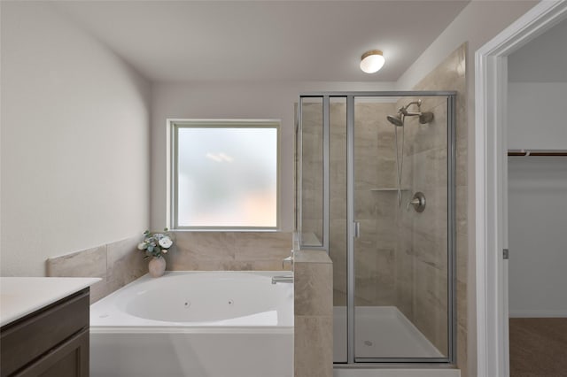 full bathroom featuring a whirlpool tub, a stall shower, a walk in closet, and vanity