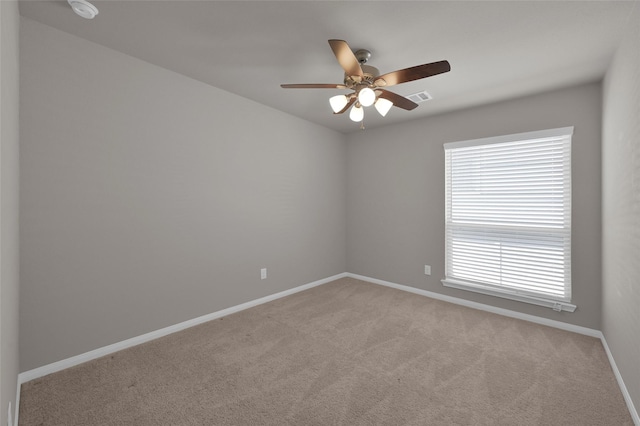 carpeted empty room featuring a ceiling fan, visible vents, and baseboards