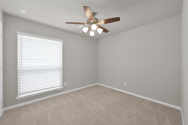 empty room with light carpet, ceiling fan, visible vents, and baseboards