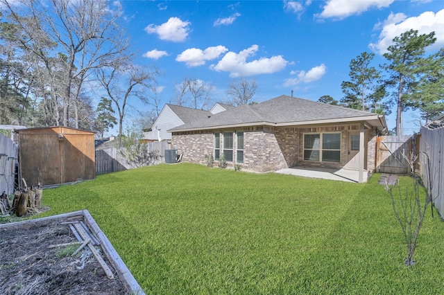 back of property with brick siding, a lawn, a patio area, a fenced backyard, and an outdoor structure