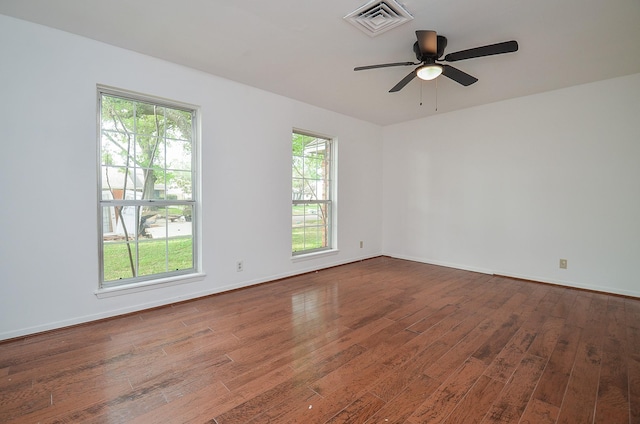 empty room featuring baseboards, ceiling fan, visible vents, and hardwood / wood-style flooring