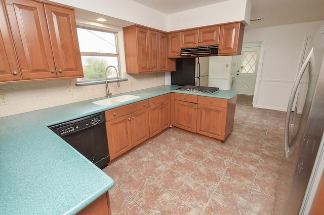 kitchen with a sink, tasteful backsplash, a peninsula, stainless steel appliances, and visible vents