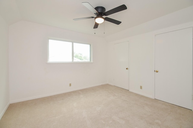 unfurnished bedroom featuring a ceiling fan, light carpet, baseboards, and lofted ceiling
