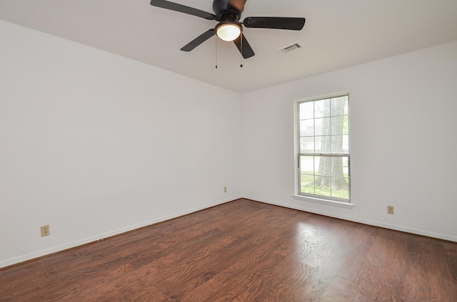 empty room with a ceiling fan, dark wood-style flooring, baseboards, and visible vents