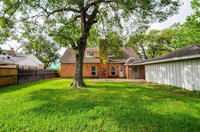 back of house with brick siding, fence, and a lawn