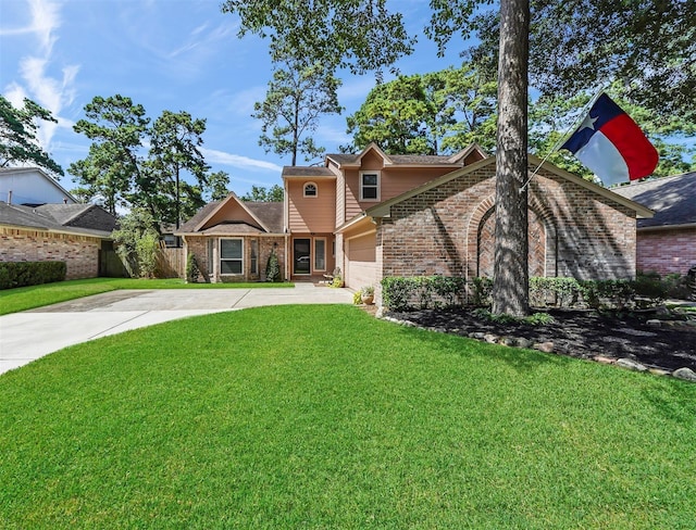 view of front facade with brick siding, fence, concrete driveway, a front yard, and an attached garage