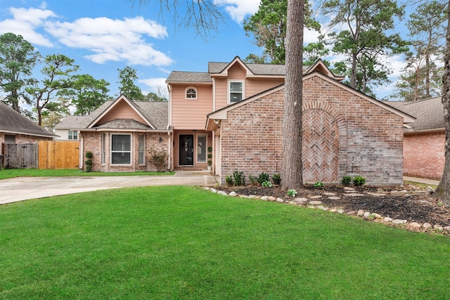 view of front of home featuring a front lawn, concrete driveway, fence, and brick siding