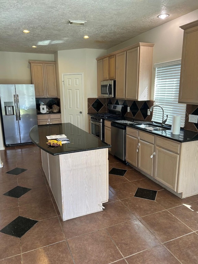 kitchen featuring visible vents, dark countertops, appliances with stainless steel finishes, dark tile patterned floors, and a sink