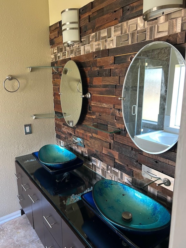 bathroom featuring a textured wall, double vanity, and baseboards