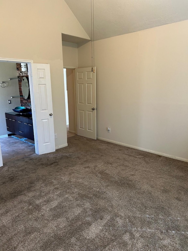 unfurnished bedroom with lofted ceiling, baseboards, and dark carpet