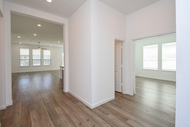 corridor featuring recessed lighting, baseboards, and wood finished floors