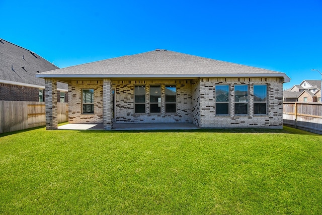 rear view of property featuring a patio area, a yard, a fenced backyard, and brick siding