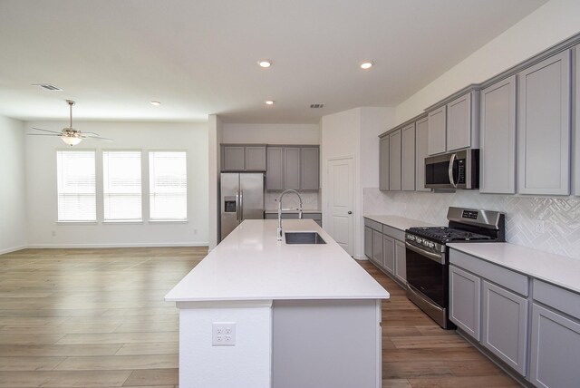 kitchen featuring decorative backsplash, gray cabinets, appliances with stainless steel finishes, and a sink