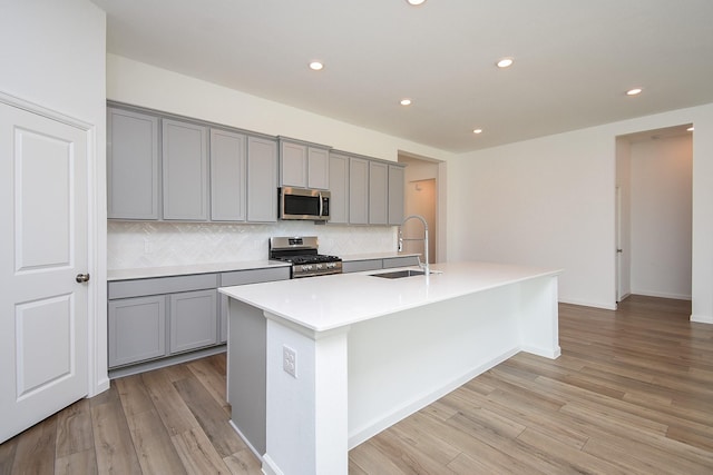 kitchen with gray cabinetry, stainless steel appliances, and a sink