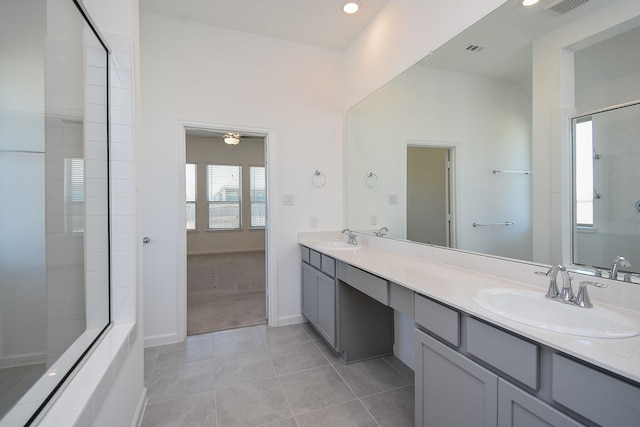 bathroom featuring tile patterned floors, tiled shower, double vanity, and a sink