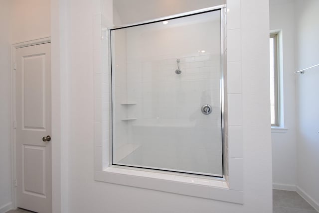 full bathroom with baseboards and a tile shower