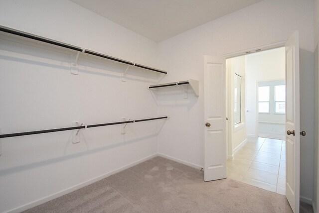 spacious closet featuring light tile patterned floors and light carpet