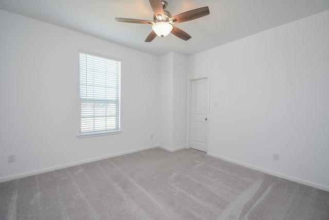 empty room featuring light carpet, baseboards, and ceiling fan